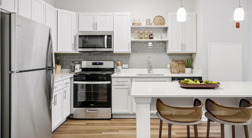 Newly Renovated Apartments Newly renovated apartment for rent The Prescott at Concord featuring a view of the new modern white kitchen cabinetry, quartz countertop island, stainless steel appliances, and hardwood flooring.