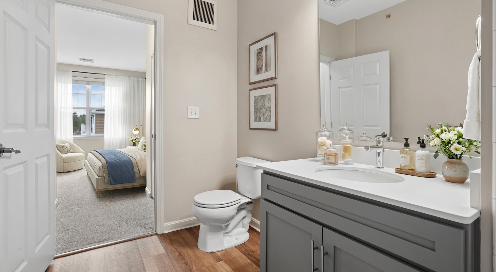View of bathroom vanity and mirror with open door leading to bedroom 