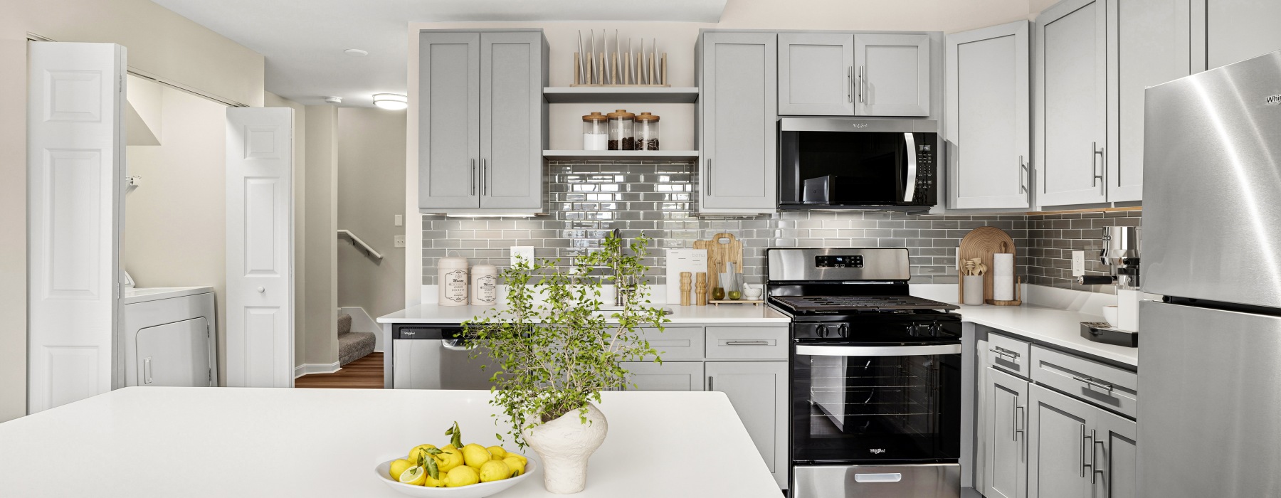 Open kitchen with plenty of natural light, a quartz kitchen island, hardwood style flooring, and grey cabinetry.